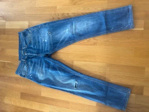 Blå slitna jeans med raka ben - Säljer ett par blå dondup. Med slitning detaljer på både fram- och baksida. 