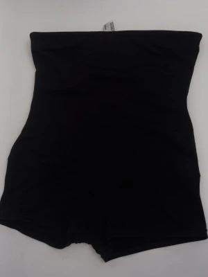 Svart shapewear från Flexees - Svart shapewear med hög midja och korta ben från Flexees by Maidenform. Tillverkad i stretchigt material som formar och slätar ut siluetten. Perfekt under klänningar eller tajta plagg för en smidig look. Använd få ggr.