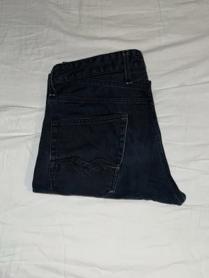 Mörkblå raka jeans w31/L34 - Snygga mörkblå jeans med rak passform och klassiska fem fickor. Jeansen har diskreta sömmar och är tillverkade i denim, vilket ger en tidlös look. Perfekta för dig som gillar enkel och stilren stil.