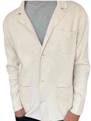 John Henric Beige Stickad Overshirt - Stilren beige kavaj från John Henric med tre utanpåfickor och klassisk krage. Kavajen har en rak passform och stängs med knappar framtill. Inte längre tillgäng i butik, högt intresse. Kontakta oss vid frågor och funderingar!