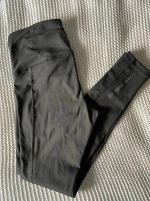 Mörkgröna träningstights från OTP - Mörkgröna träningstights från OTP med hög midja och sidoficka. Tillverkade i ett stretchigt och mjukt funktionsmaterial som sitter skönt och följer kroppen. Perfekta för gym, löpning eller yoga. Enkel och stilren design.
