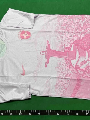 Vit och rosa Nike fotbollströja  - Snygg vit och rosa fotbollströja från Nike med motiv av Kristusstatyn i Rio de Janeiro och stadssilhuett. Tröjan har rund hals, korta ärmar och är tillverkad i ett lätt, ventilerande funktionsmaterial. Perfekt för träning eller match.