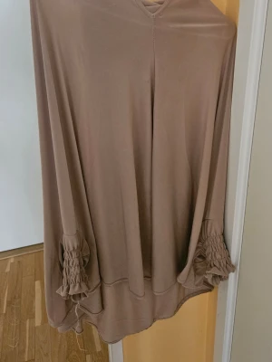 Beige Abaya med rynkade kanter - Säljer en Abaya med snygga rynkade och volangprydda kanter. Sjalen är mjuk och har en flowy form som ger ett elegant intryck. 