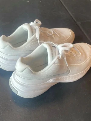 Vita Nike sneakers med tjock sula - Fräscha vita sneakers från Nike med en chunky sula och diskret silverfärgad swoosh på sidan. Ovandelen är i mesh och syntetmaterial för bra andningsförmåga. Klassisk snörning och låg modell som passar till många olika stilar. Original pris: 989 kr