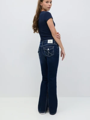 Mörkblå bootcut jeans från Gina tricot  - Snygga mörkblå bootcut jeans från Gina tricot med kontrasterande vita sömmar och dekorativa bakfickor med lock och knapp. Jeansen har en klassisk femficksdesign och en vit patch med hjärtdetaljer bak i midjan.