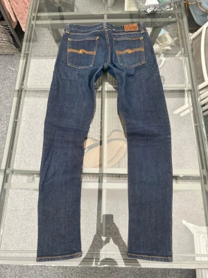Nudie Jeans Skinny Lin W31/L32 - Säljer ett par Nudie Jeans Skinny Lin i mörkblå denim. Sjukt clean wash och riktigt bra passform med skinny/slim fit. Storlek W31/L32 och i väldigt bra skick. Orange sömmar och klassiska Nudie-detaljer gör att de sitter fett i både streetwear och clean outfits. Lite stretch för bättre komfort. Perfekta everyday jeans som passar till sneakers, hoodie eller skjorta.  📏 W31/L32 👖 Skinny Lin 🎨 Dark blue denim ✨ Väldigt bra skick