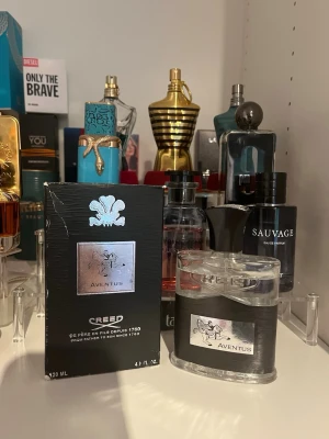 Creed Aventus Eau de Parfum 120ml - Creed Aventus är en exklusiv parfym med en elegant svart och silverfärgad flaska. Märket Creed är känt för sina lyxiga dofter och flaskan har en stilren design med metallisk etikett. Förpackningen är svart med silverdetaljer och rymmer 120 ml Eau de Parfum.