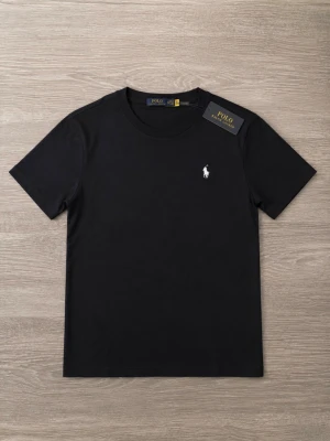 Svart t-shirt från Polo Ralph Lauren - En stilren svart t-shirt från Polo Ralph Lauren med klassisk passform och rund hals. T-shirten har korta ärmar och en liten vit broderad logga på bröstet. Perfekt basplagg i mjuk bomull.