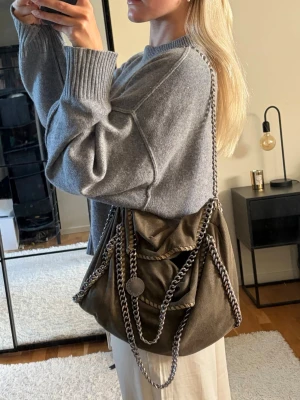 Grön Stella McCartney väska - Så snygg grön väska från Stella McCartney! Säljer då den tyvärr inte kommer tillanvändning längre. Är i bra skick men har tappat ena knappen för att stänga den (se sista bilden), men den går annars att använda som vanligt 💗