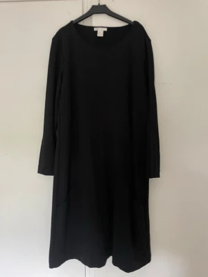 Svart långärmad klänning - En stilren svart klänning med lång ärm och rund halsringning. Klänningen har en rak passform och är tillverkad i ett mjukt material som känns bekvämt mot huden. Perfekt för dig som gillar enkel och klassisk stil.