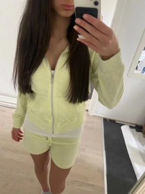 Gul velour loungewear-set med hoodie - Mysigt loungewear-set i ljusgul velour med dragkedja framtill och huva. Setet består av en hoodie och matchande shorts med resår i midjan. Perfekt för chill dagar hemma. Snygg och enkel design.