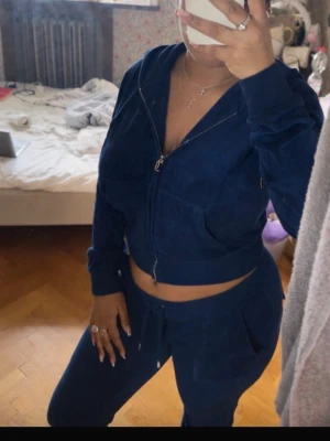 Mörkblå velourset från Juicy Couture - Säljer ett mörkblått velourset från Juicy Couture med zip hoodie och matchande byxor. Hoodien har dragsko och fickor, byxorna har resår i midjan och snörning. Perfekt för chill dagar hemma eller när du vill vara extra comfy.