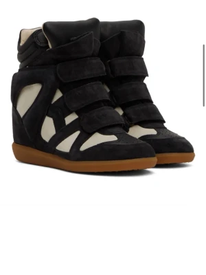 Kioss svarta höga sneakers - Höga sneakers från kioss i svart mocka med vita detaljer. Skorna har flera kardborreband, brun gummisula samt en unik design med cut-outs och en uppbyggd kilklack som ger extra höjd. De är välanvända och inte i bästa skick, vilket också återspeglas i priset.  ￼