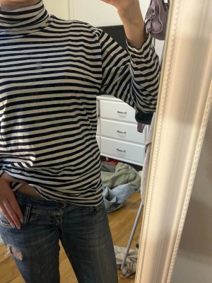 Randig polotopp i blått och vitt - Snygg långärmade polotopp med marinblå och vita ränder. 