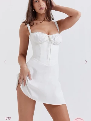 House of cb - CARLOTTA White Corset Mini Dress - Our 'Carlotta' dress in white is effortlessly chic, making it perfect for Spring vacations. It's cut from stretch cotton that's fitted with a corseted bodice to cinch the waist and has a beautiful lace up back. The gathered bust has a drawstring tie for the perfect fit and the thigh skimming mini hem has a pretty a-line shape. Please note that there is a faint stain ( see last picture) 