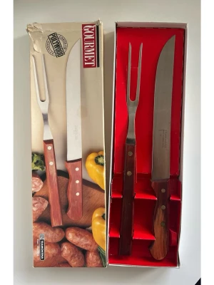 Gourmet trancherset i rostfritt stål - Stilrent set med en kniv och en gaffel och slipkniv från Tramontina Gourmet. Klassiskt Trancherset / grillbestick.  Levereras i sin originalförpackning. Kartongen har sett bättre dar, men besticken är i mycket gott skick, som nya!