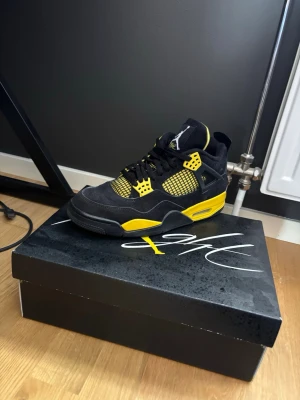 Air Jordan 4 Retro thunder  - Säljer ett par Air Jordan 4 Retro sneakers i svart och gul. Skorna har en klassisk siluett med meshpaneler, passar perfekt till sommaren och vintern , knappt andvända 