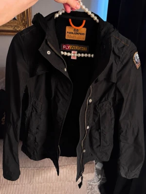 Parajumpers lättvikts jacka  - Äkta parajumper jacka Färg svart Den är mindre i storleken så passar någon som är Small, el en mindre medium. Lätt viktig och tunn.  Passar vår ,sommar, sen sommar.  Har använt den en gång sen gick jag upp i vikt och fick ingen användning för den. Den är super fin.  Jackan är hel och ren!