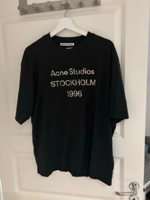 Svart Acne Studios t-shirt - Säljer en svart t-shirt från Acne Studios med trycket 'Acne Studios STOCKHOLM 1996' på bröstet. Klassisk rund hals och korta ärmar. Perfekt basic med en clean look och oversized passform.