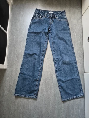 Blå raka jeans från Gina  - Säljer ett par klassiska blå jeans från Gina Tricot med rak passform och fem fickor. Jeansen har låg midja.