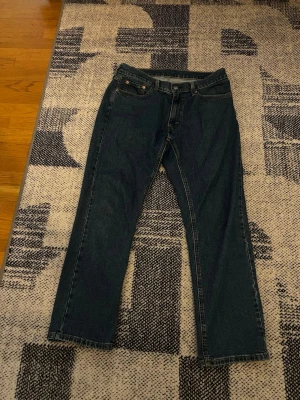 Levis 541  - Säljer ett par klassiska mörkblå jeans från Levi's med rak passform och fem fickor. Jeansen har den ikoniska röda Levi's-lappen bak och är tillverkade i slitstark denim. Perfekta för en avslappnad och tidlös stil.