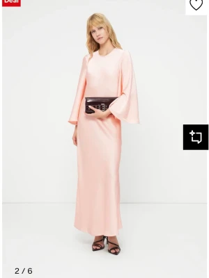 Ljusrosa långklänning med vida ärmar - vero moda - Elegant ljusrosa långklänning i ett glansigt material med rund halsringning och vida, långa ärmar. Klänningen har en rak siluett och faller mjukt längs kroppen, perfekt för en stilren och modern look. Liten i storlek, L sitter som M