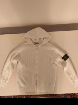 Stone Island  - Vit Stone Island-kofta i fint skick. Använd under våren och passar perfekt även till sommaren. Inga problem eller defekter. QR-kod finns för äkthetskontroll. Säljes inför sommaren då den inte används lika mycket.