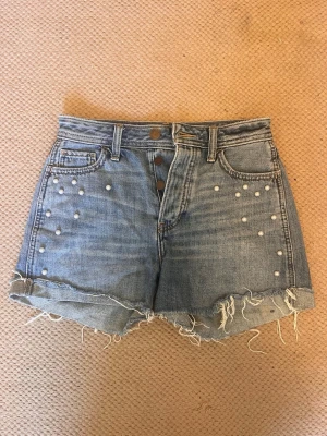 Jeansshorts - Fina jeansshorts från Hollister i stl w23, har pärlor som detaljer. Bara att skriva vid frågor