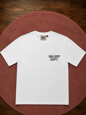 Vit Gallery Dept. t-shirt - Snygg vit t-shirt från Gallery Dept. med svart tryck fram och stort tryck på ryggen där det står 'GALLERY DEPT. HOLLYWOOD, CA.'. Klassisk passform och rund hals. Perfekt till streetwear-stilen.