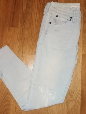 Ljusblå slitna jeans med hål från TOPSHOP w26 L32 - Säljer ett par ljusblå jeans med trendigt sliten look och hål vid knäna. Klassisk femficksmodell med smal passform. . Perfekta för dig som gillar en avslappnad och cool stil.. De är mjuka och följsamma och sitter superfint på. Byxan är i fint använt skick, har dock två små prickar längst nere vid bensluten som går säkert bort med en tvätt :)