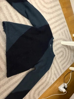 Mörkblå stickad tröja Gina Tricot - Mysig stickad tröja från Gina Tricot i mörkblått och svart med diagonal färgblockdesign. Tröjan har rund halsringning och långa ärmar. Perfekt för kalla dagar och enkel att matcha med jeans eller kjol.