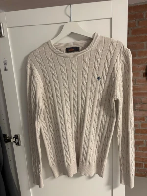 Beige kabelstickad tröja Morris - En fin kabelstickad Morris tröja som är köpt på NK. Har tyvärr växt ur mig så säljer den, använd men i mycket fint skick. Storlek M och priset går att diskutera. Hör av er vid funderingar!