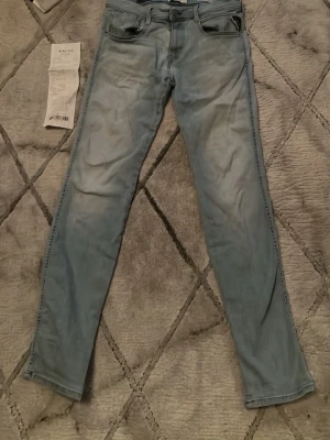 Ljusblå jeans från Replay - Säljer ett par ljusblå skinny jeans från Replay med klassisk femficksdesign och dragkedjegylf. Jeansen har en snygg tvättad look och raka ben. Perfekta för dig som gillar en avslappnad men ändå stilren vibe. Köpta på NK.