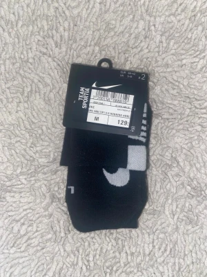 Svarta strumpor från Nike - Säljer ett 2-pack svarta strumpor från Nike med vit logga. Perfekta till sneakers och träning. Sköna och stilrena strumpor i mjukt material som sitter bra på foten. 