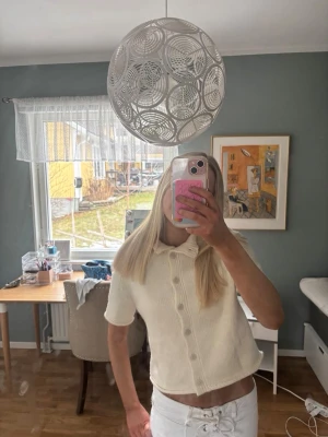 Vit kortärmad stickad kofta - Säljer en söt vit stickad kofta med korta ärmar och stora knappar framtill. Helt oanvänd.  Original storleken är L men jag skulle uppskatta den som S. Jag har vanligtvis S i kläder och den satt bra på mig. 