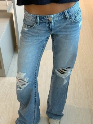 Ljusblå slitna loose bootcut jeans - Superfina ljusblå loose bootcut jeans / baggy jeans med slitningar och hål på båda knäna. Lågmidjade. Storlek S och i fint skick! Slutsålda, nypris 429,95 kr🥰🥰🥰