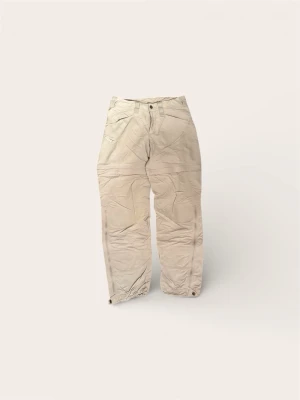 Haglöfs Convertible Vandringsbyxor (Dam) – Strl S - Säljer ett par mångsidiga och tekniska vandringsbyxor från Haglöfs i damstorlek S. Modellen är "convertible", vilket innebär att benen enkelt kan zippas av med dragkedjor för att förvandla byxorna till shorts när temperaturen stiger.  Märke: Haglöfs.  Färg: Beige / Ljus sand.  Storlek: Small (Dam).  Funktion: Zip-off ben, praktiska fickor och hållbart material för outdoor-liv.  Skick: Mycket fint skick! Byxorna är hela och alla dragkedjor fungerar 