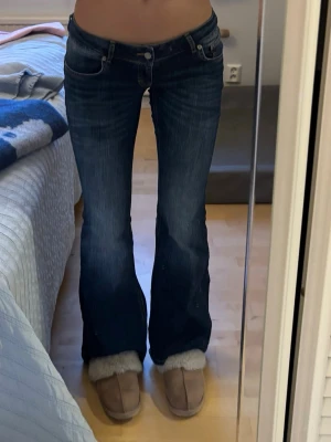 Mörkblå bootcut jeans Blaze - Säljer ett par mörkblå bootcut jeans med låg midja och klassiska fem fickor. Jeansen har snygga kontrastsömmar och en läderpatch med logga bak i midjan. Perfekta för dig som gillar en retro och avslappnad stil. 38 men passar 36. Oanvända 