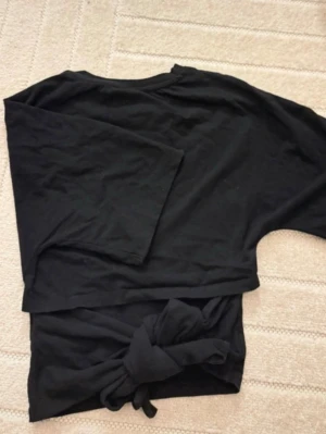 Svart knyt topp från lager 157 - Säljer en svart topp med knyt bak i midjan. Kommer tyvärr inte till användning så därför säljer jag den.