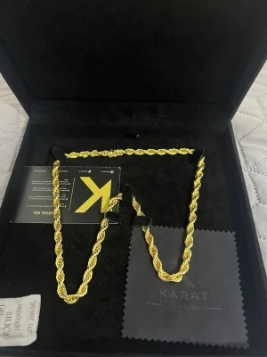 Cordel kedja 6mm - Snyggt halsband från Karat med repkedje-design i guldfärg. Halsbandet har en robust låsdetalj och levereras i en elegant svart ask med putsduk. Perfekt accessoar för dig som vill sticka ut med en trendig och exklusiv look.