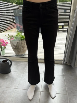 Svarta bootcut jeans med låg midja - Snygga svarta bootcut jeans med låhmidja och klassiska fem fickor. Jeansen är bootcut. Perfekta för dig som gillar en stilren look med lite edge. jättefina till sommaren med en fin ljus topp💕Modellen är 166 cm och byxorna är i storlek 158