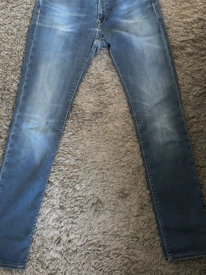 Blå Replay Hyperflex jeans - Säljer ett par blå Replay Hyperflex jeans med snygg tvätt och lätt slitna detaljer. Jeansen har klassisk femficksmodell, dragkedjegylf och smal passform. Perfekta för dig som gillar stretchigt material och en modern look. OBS! Små i storleken