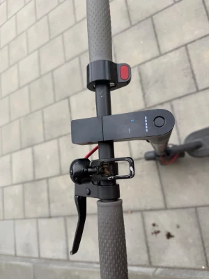 Svart elscooter med display - Elscooter i svart med digital display på styret, grå handtag och bred fotplatta med mönster. Utrustad med handbroms och LED-indikatorer för batterinivå. Perfekt för smidig transport i stan.