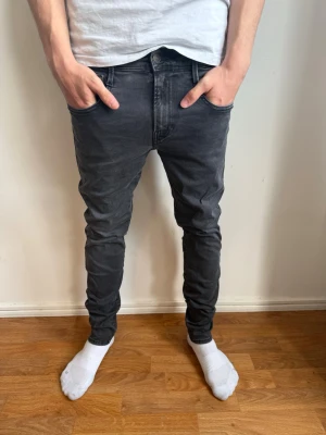 Mörkgrå slim fit jeans från Replay - Säljer ett par mörkgrå slim fit jeans från Replay med klassisk femficksdesign och smal passform. Jeansen har normal midja och är tillverkade i stretchigt material för extra komfort. Perfekta för en avslappnad och trendig look.