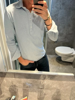 Ljusblå henley skjorta i bomull - Säljer en stilren ljusblå henley skjorta med lång ärm och knappar framtill från John Henric. Passar perfekt nu till sommaren. Jag på bilden är 188cm och bör storlek S vilket är aningen för litet. Hör av er vid fler frågor:)