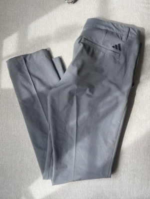 Adidas Golfbyxor – Grå – Strl 28/30 - Säljer ett par stilrena och bekväma golfbyxor från Adidas. Perfekta både på golfbanan och till en mer uppklädd vardagsstil. Stretchigt material som ger bra rörelsefrihet och hög komfort.  Märke: Adidas Storlek: 28/30 Färg: Grå Skick: Mycket fint skick  • Lätt och följsamt material • Klassisk passform • Två framfickor och två bakfickor • Diskret Adidas-logga baktill • Perfekta för golf, arbete eller vardag