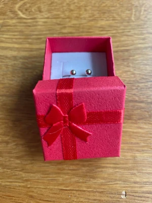 Små silverfärgade pärlörhängen - Ett par stilrena och minimalistiska örhängen i silverfärg, formade som små kulor. Levereras i en söt röd presentask med röd rosett. Perfekta för dig som gillar enkel och klassisk stil.