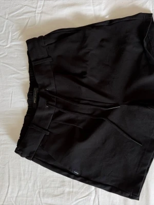 Svarta shorts med snörning från Only - Säljer ett par svarta shorts från Only med snörning i midjan och elastisk resår baktill. Shortsen har en clean look med fickor både fram och bak, och är tillverkade i ett mjukt bomullsmaterial. Perfekta för en avslappnad och stilren outfit.