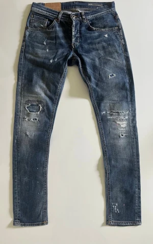 Blå dondup jeans - Säljer ett par blå skinny jeans med slitningar och hål på benen. Jeansen har klassisk femficksdesign, Perfekta för en avslappnad streetwear-look.