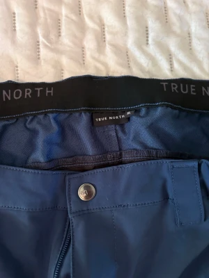 Blå frilufts byxor från True North XL - Säljer ett par blå frilufts byxor från True North i storlek XL.dragkedjor vid fickorna och nedtill på benen. Perfekta då man  ska ut och vandra/ va i skogen. 